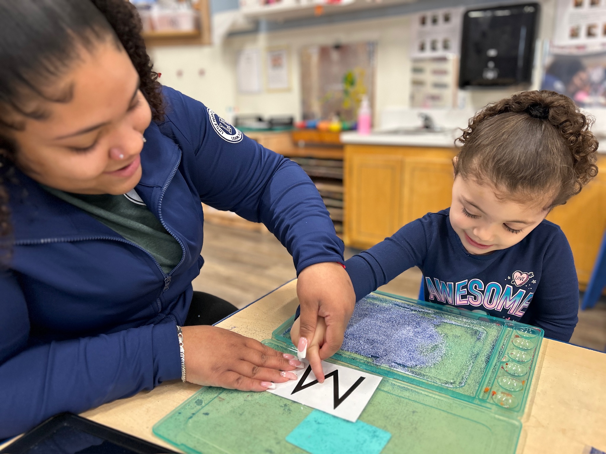 Teacher helping child practice letter writing