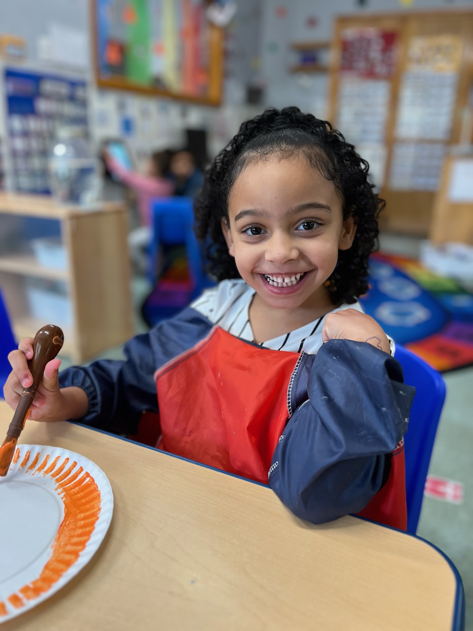 Girl grinning with paintbrush during art time