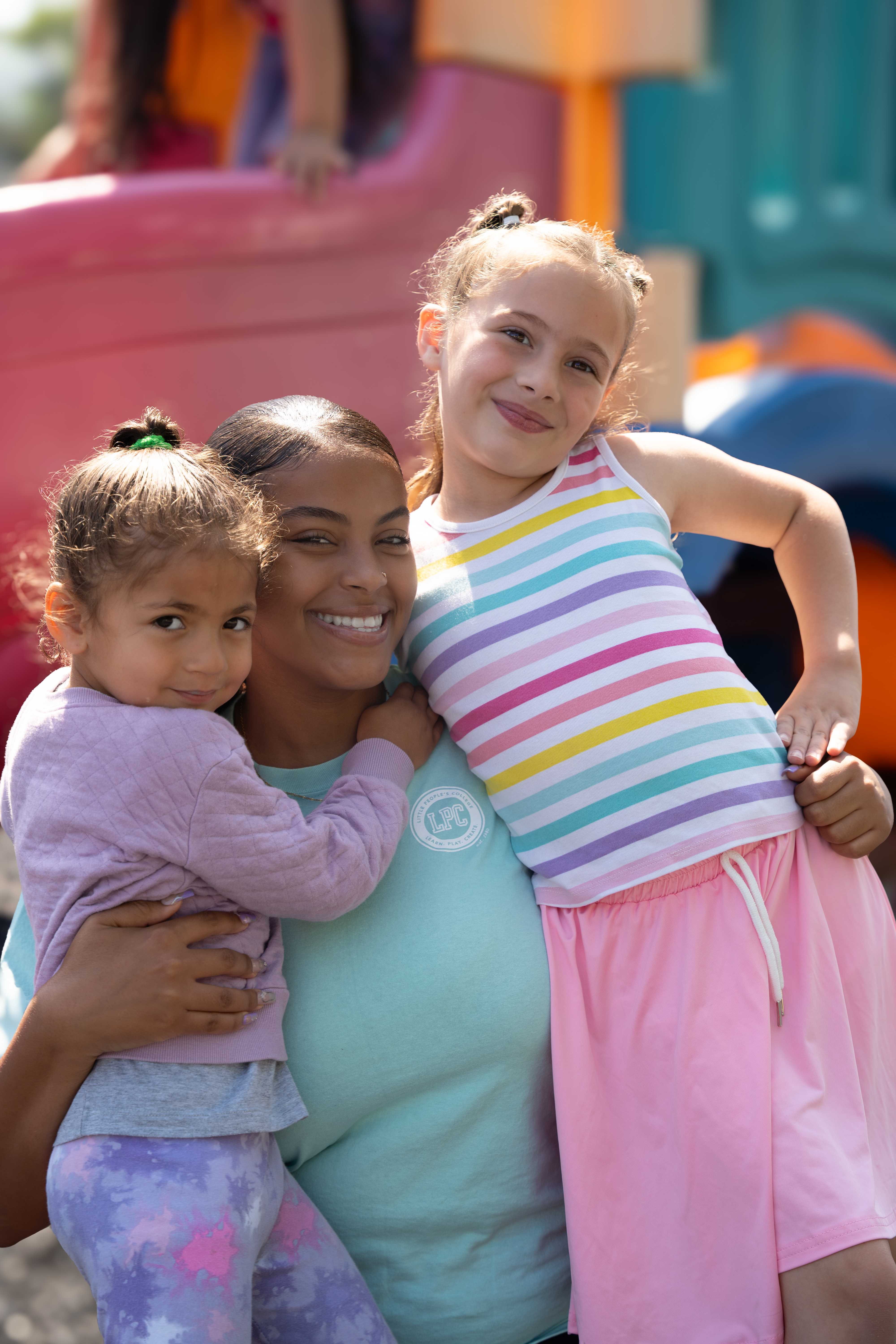 LPC teacher hugging two children at the playground