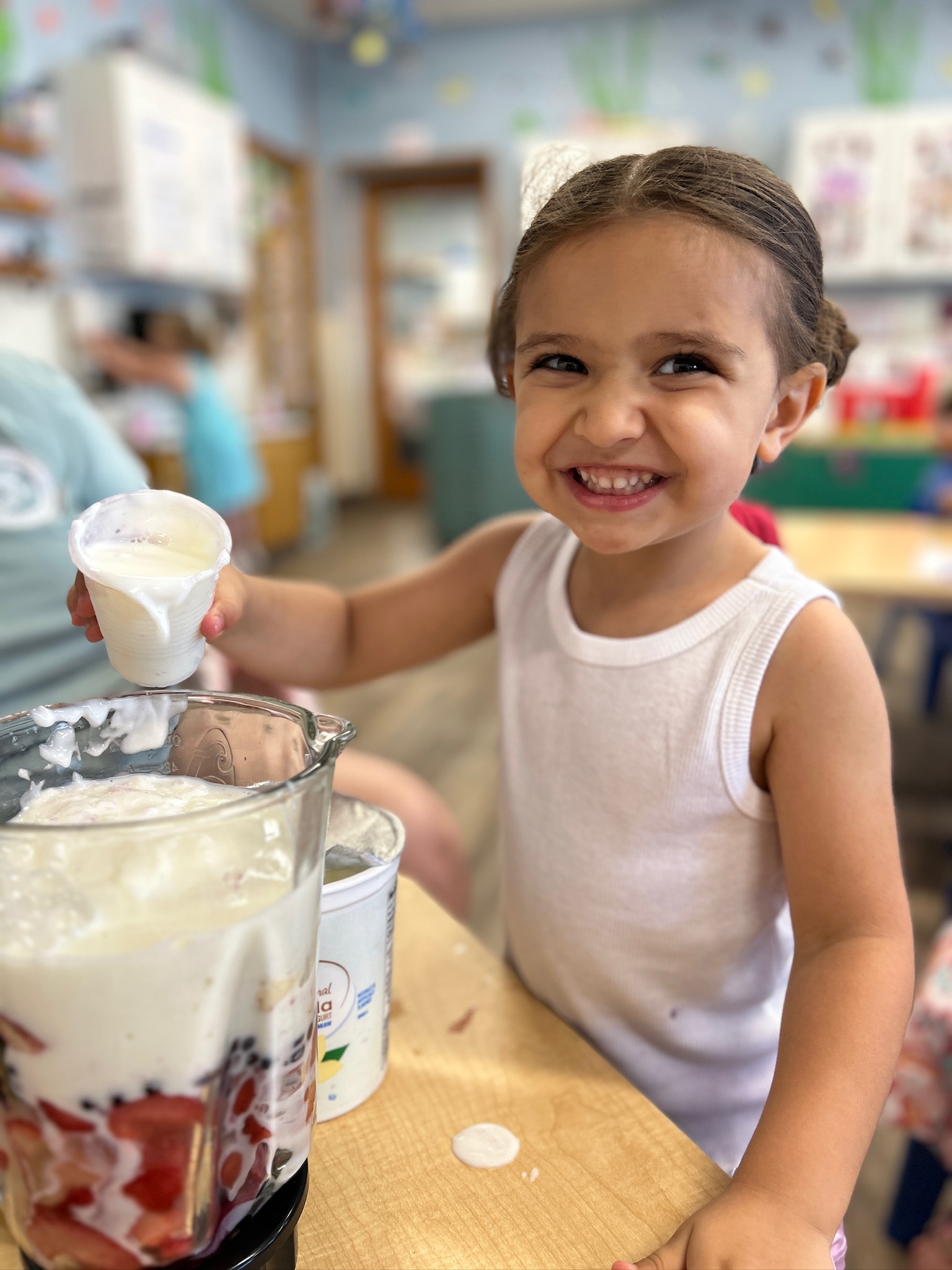 Child helping prepare a healthy fruit smoothie at Little People's College