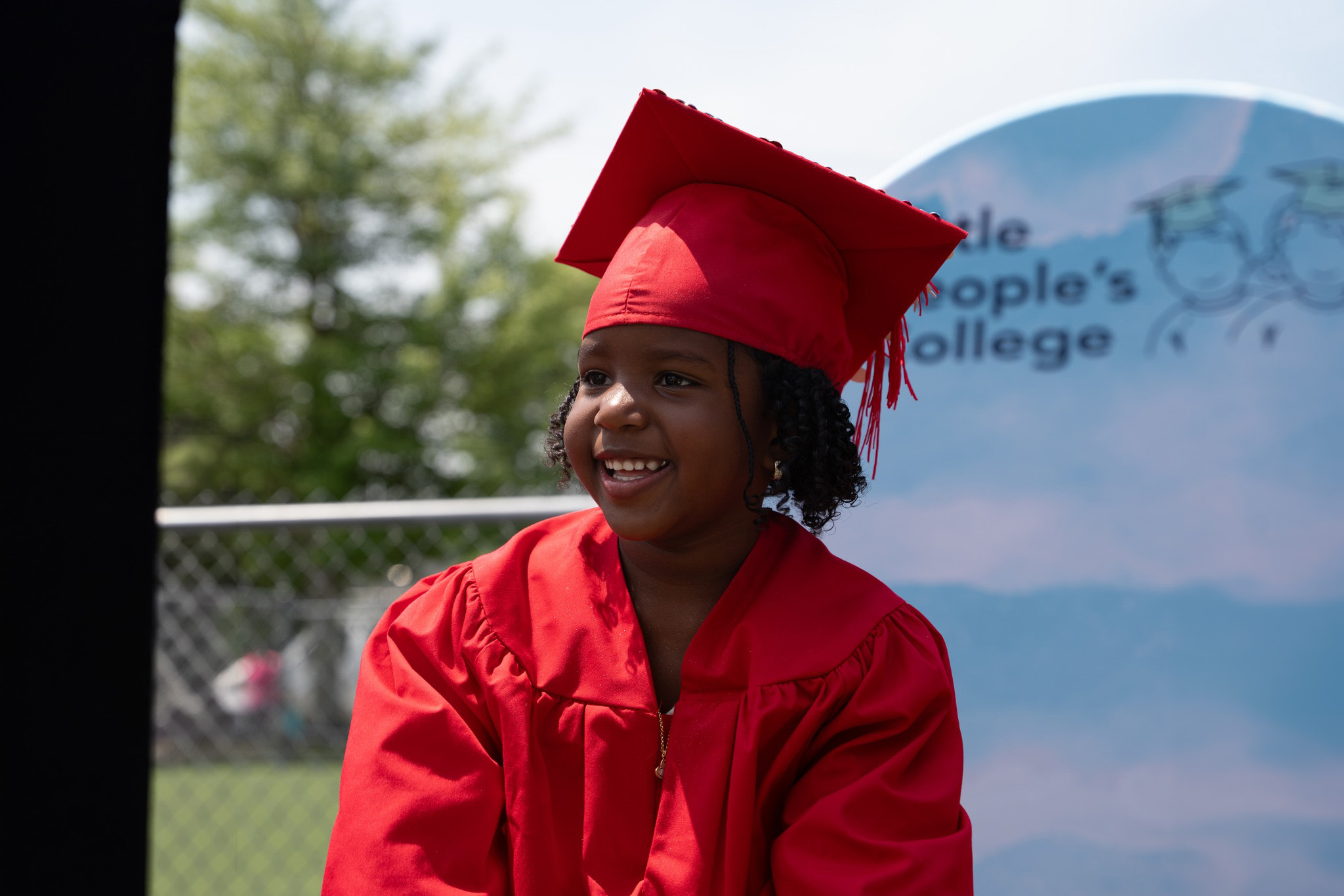 Pre-K graduates in red caps and gowns celebrating at their graduation ceremony