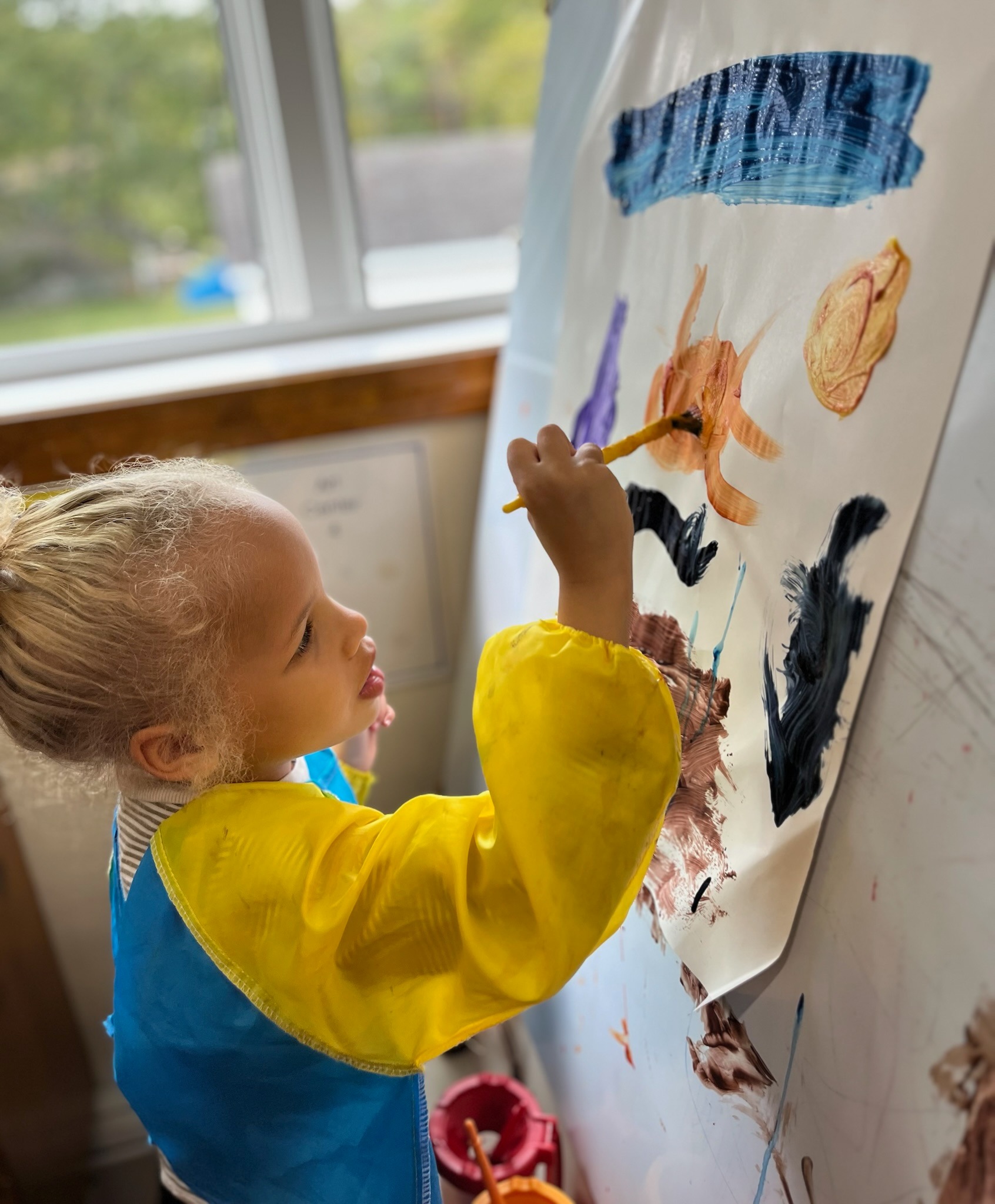 Girl painting at easel during art time