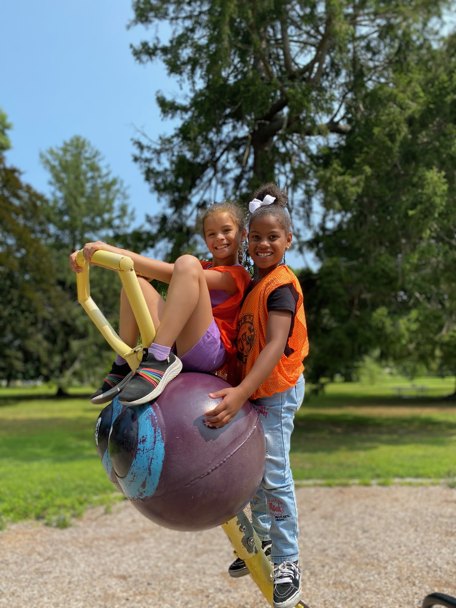 Two friends playing on playground equipment during summer